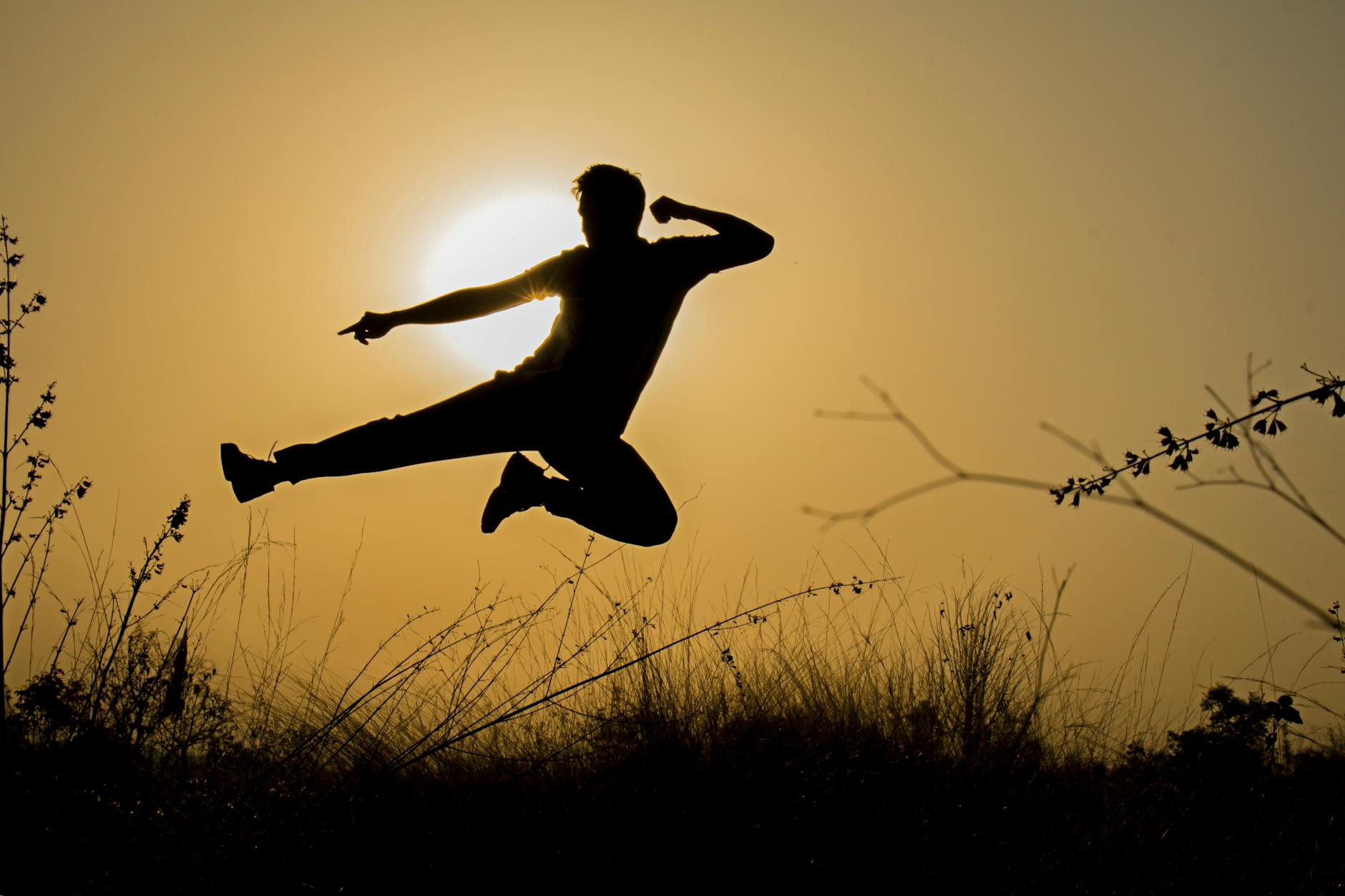 A dynamic silhouette of a man performing a jump against the sunset in Wadgaon, India.