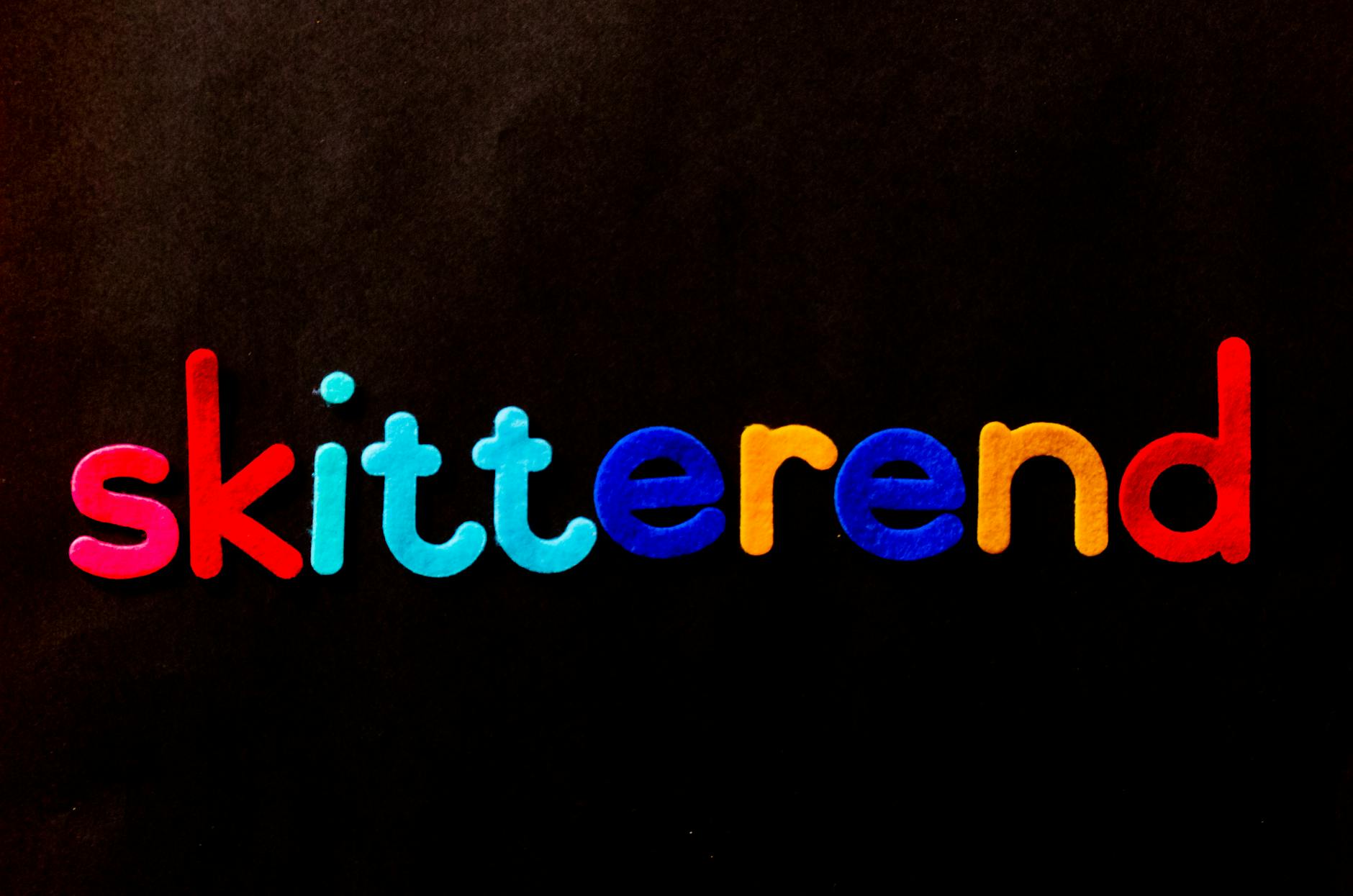 Vibrant multicolored alphabet letters spelling 'skitterend' on a dark backdrop.