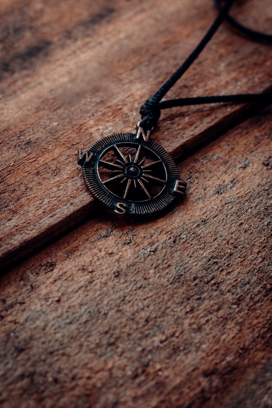 A close-up of a compass pendant on a textured wooden table, emphasizing urban exploration themes.