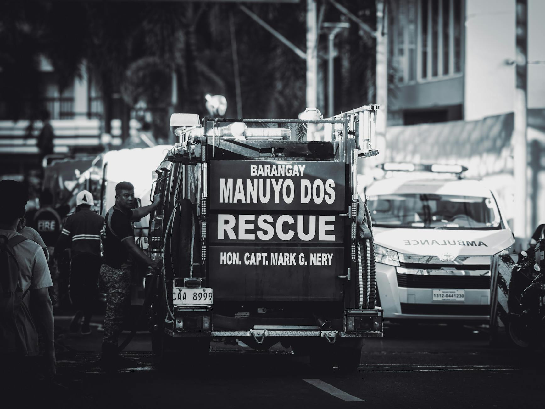 Monochrome scene featuring rescue vehicles and personnel on a busy urban street.
